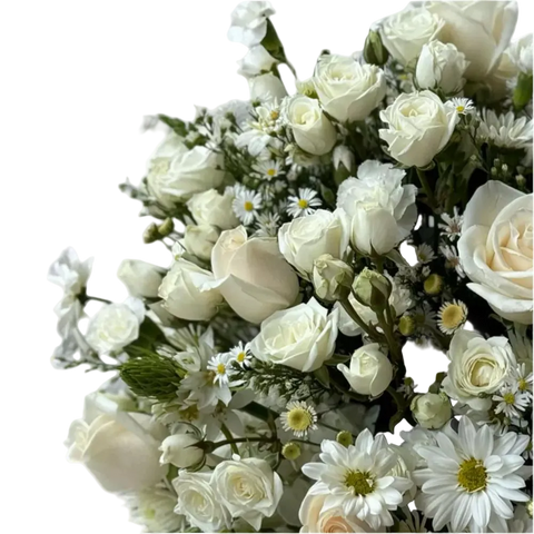 Vista cercana de los botones de rosas blancas, las margaritas y el follaje que complementan la composición floral