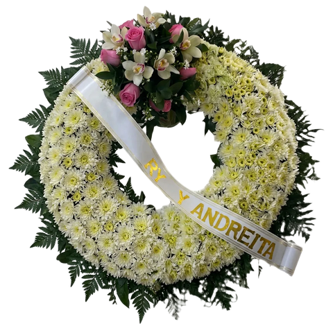 Primer plano de crisantemos blancos y crema con follaje verde y cinta conmemorativa